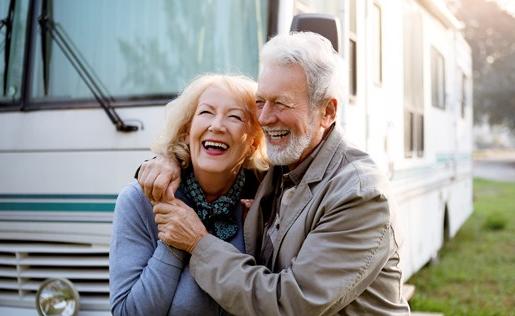 Older couple hugging outside their RV